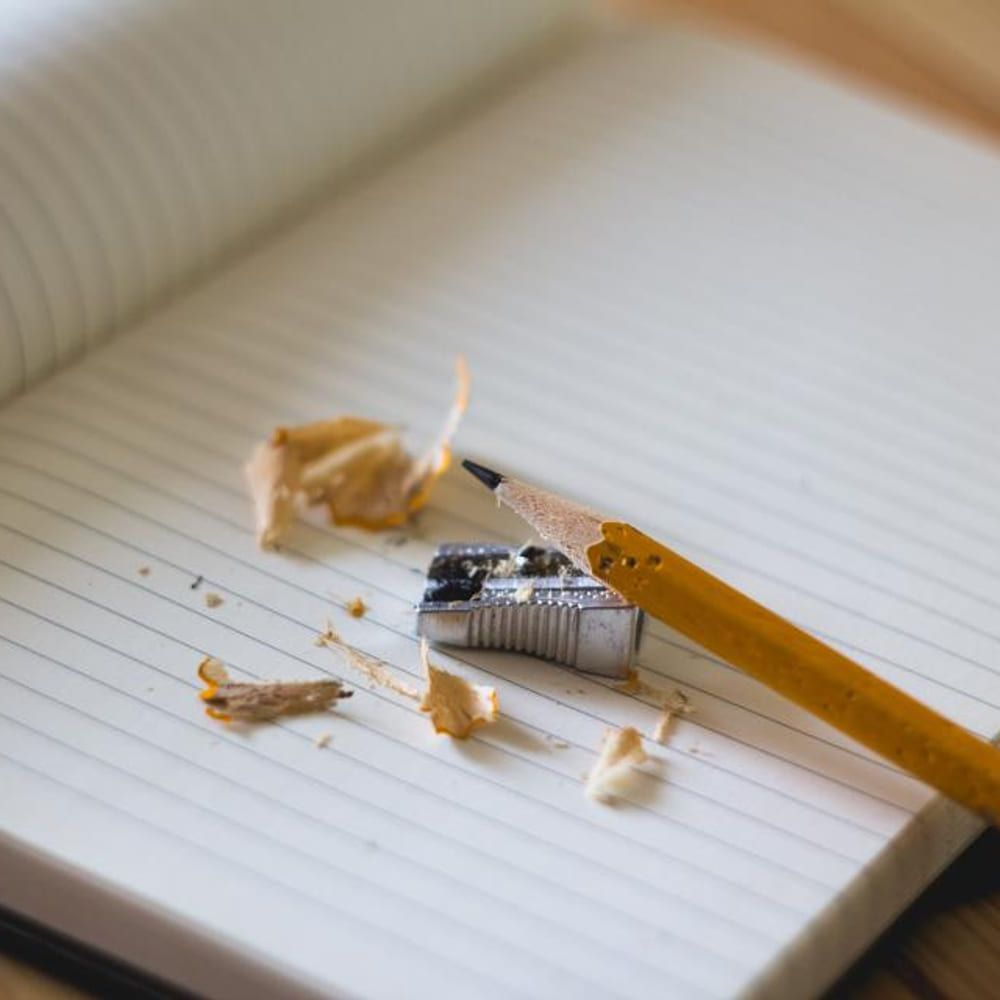 A pencil and shavings on a lined notebook