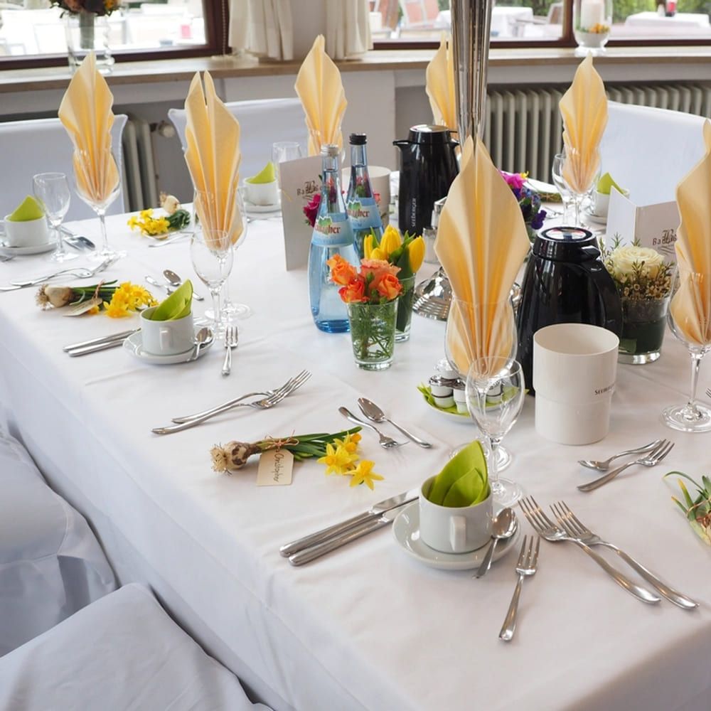A long table laid with cloth, flowers and place settings for an event