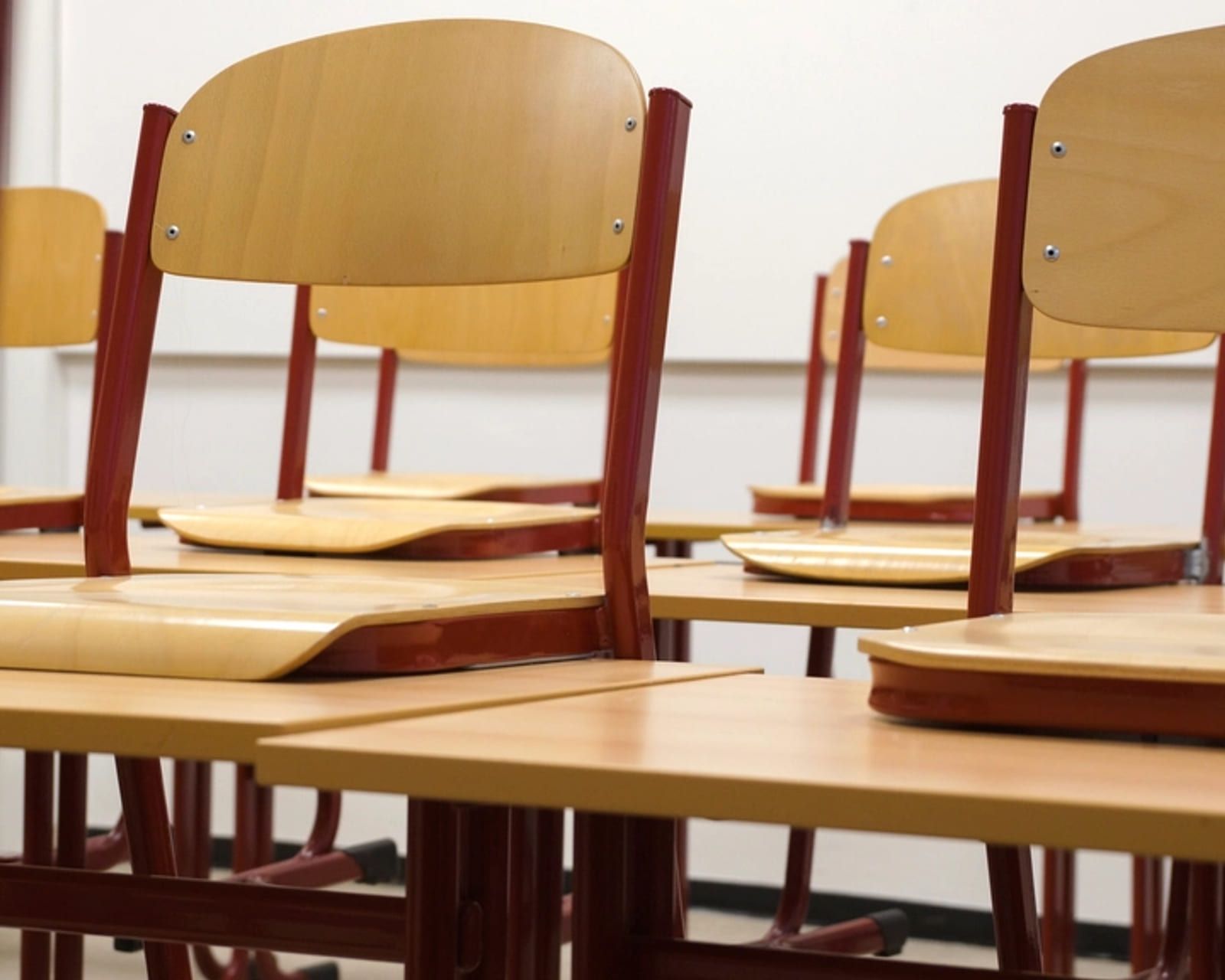 Chairs stacked upside-down on desks in an empty classroom