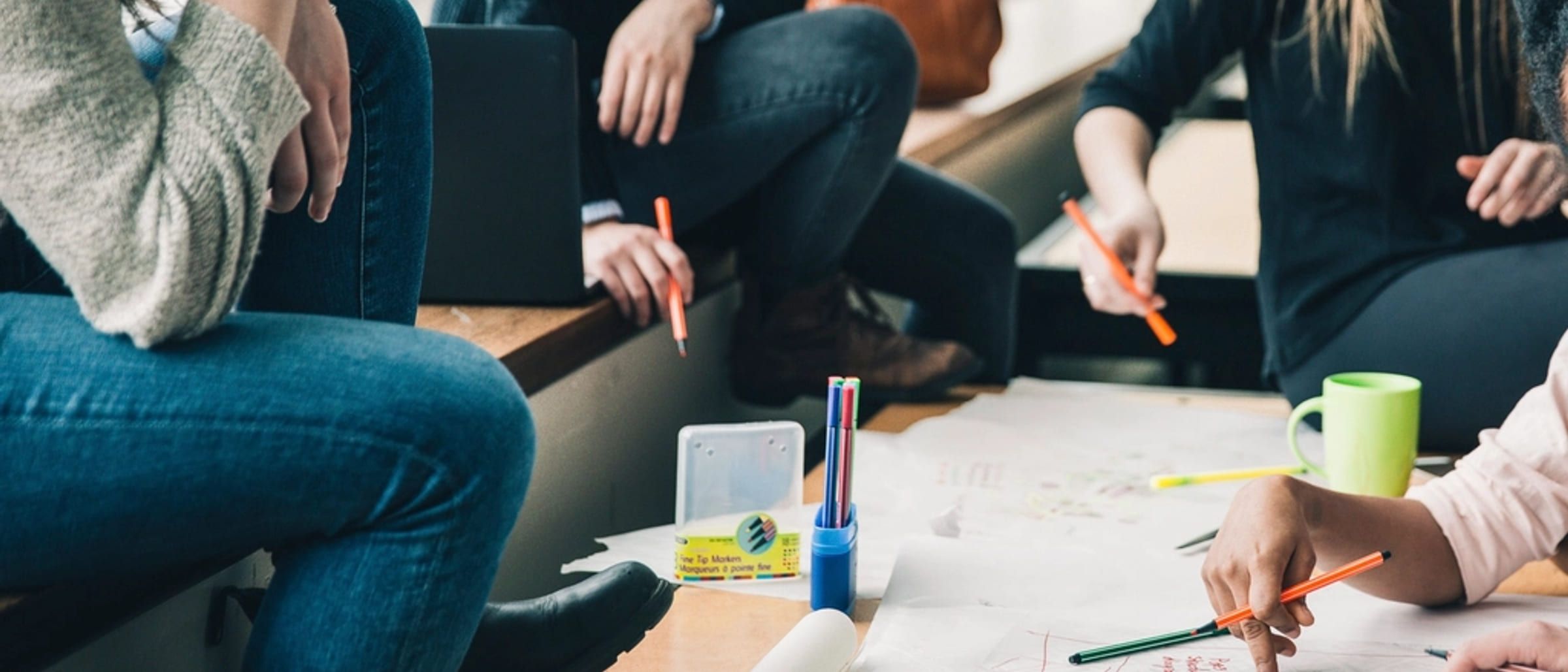 People working together around a table covered with paper and pens, seen wide