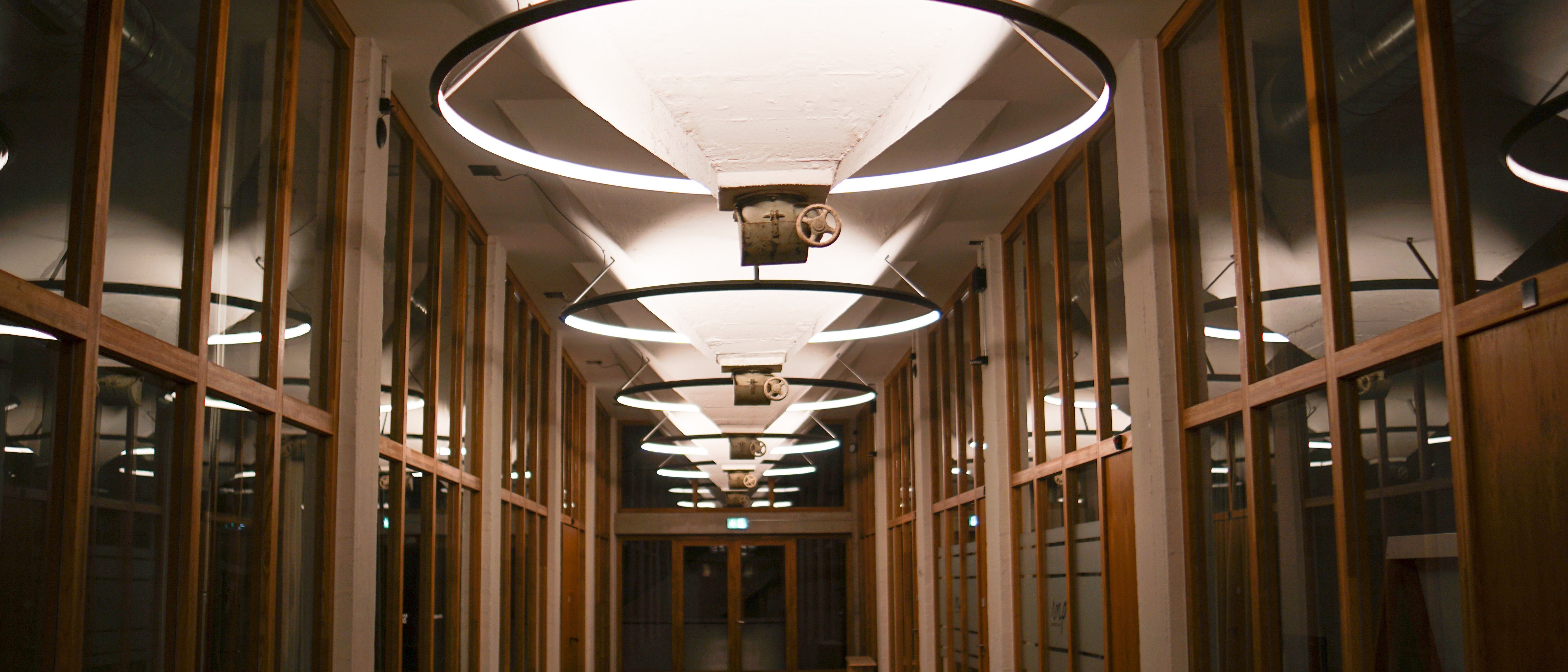 A long glass-walled corridor leading to a set of double doors